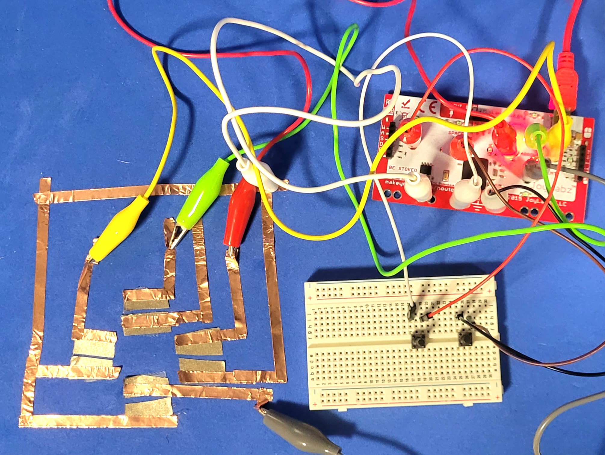 A photo of an iteration of the button circuit, now with full directional inputs achieved through a copper tape circuit.